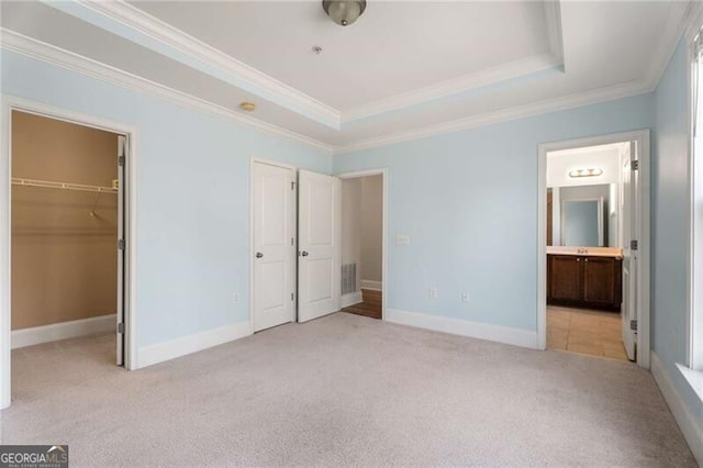 unfurnished bedroom with a tray ceiling, carpet floors, visible vents, and ornamental molding