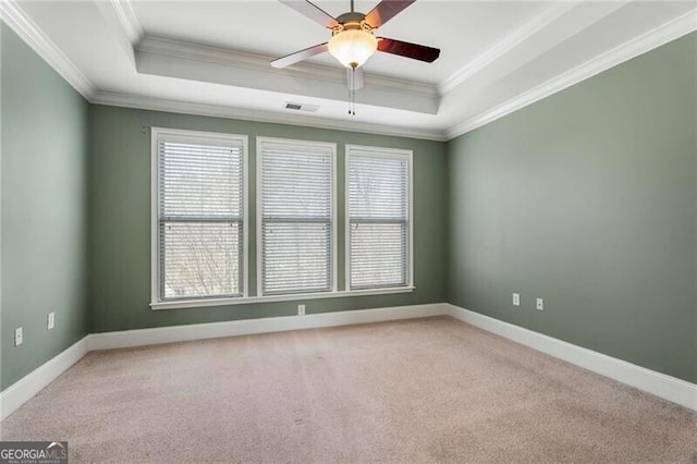 empty room featuring light carpet, crown molding, a tray ceiling, and visible vents
