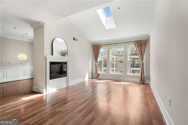 unfurnished living room with crown molding, a glass covered fireplace, wood finished floors, and visible vents