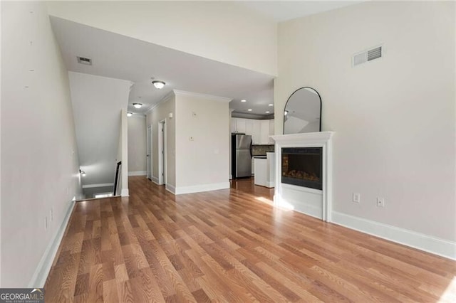 unfurnished living room featuring baseboards, visible vents, a fireplace, and light wood-style floors
