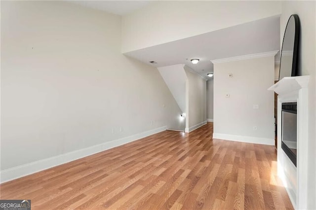 unfurnished living room with a glass covered fireplace, baseboards, and light wood-style floors