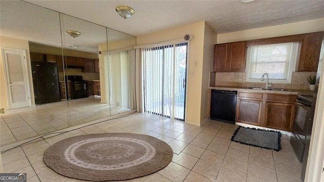 kitchen with light tile patterned floors, black appliances, tasteful backsplash, and a sink