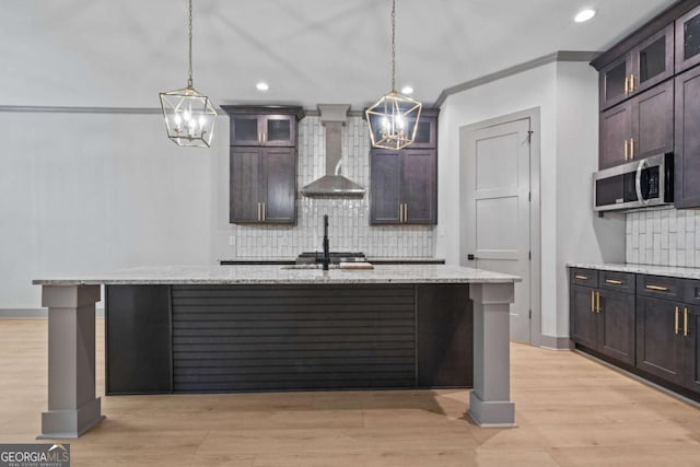 303 Tumbling Shoals Ct, Gray, GA 31032 - kitchen with stainless steel microwave, light stone counters, wall chimney exhaust hood, and a chandelier