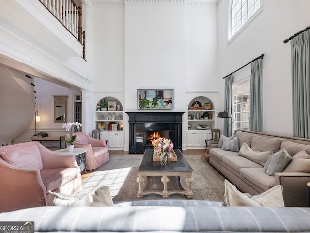 living area featuring a towering ceiling, a tile fireplace, and built in features