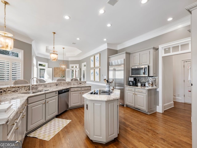 kitchen with light wood finished floors, ornamental molding, appliances with stainless steel finishes, a sink, and a center island