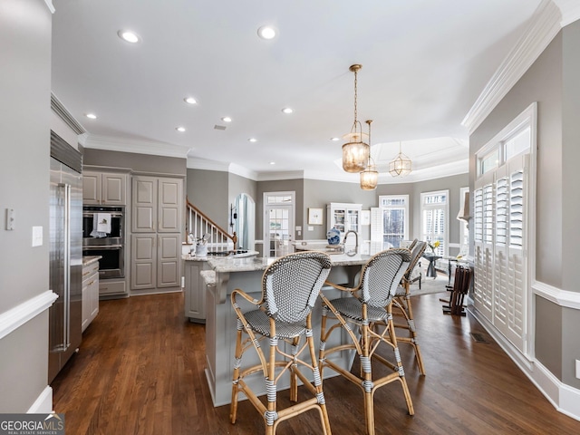 kitchen featuring a kitchen breakfast bar, recessed lighting, gray cabinets, dark wood-style floors, and a large island