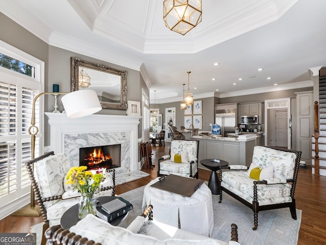 living area featuring recessed lighting, ornamental molding, dark wood-type flooring, a notable chandelier, and a fireplace