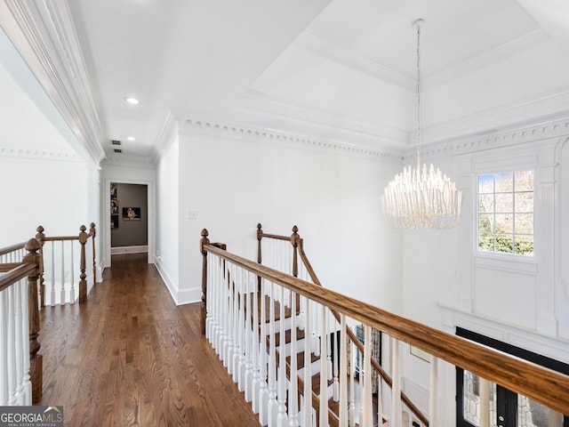 hall featuring dark wood-style flooring, an upstairs landing, crown molding, and a notable chandelier