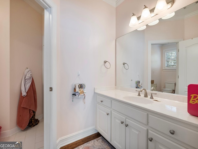 bathroom with toilet, vanity, baseboards, visible vents, and ornamental molding