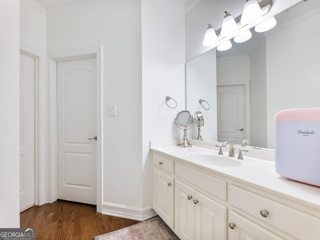 bathroom with baseboards, crown molding, wood finished floors, and vanity