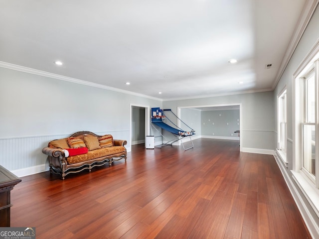 living area with a wainscoted wall, crown molding, wood finished floors, and recessed lighting