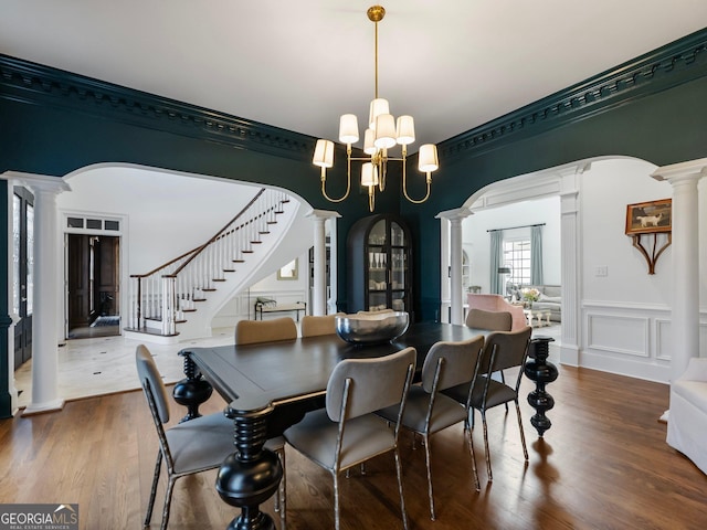 dining area with an inviting chandelier, arched walkways, stairway, and ornate columns