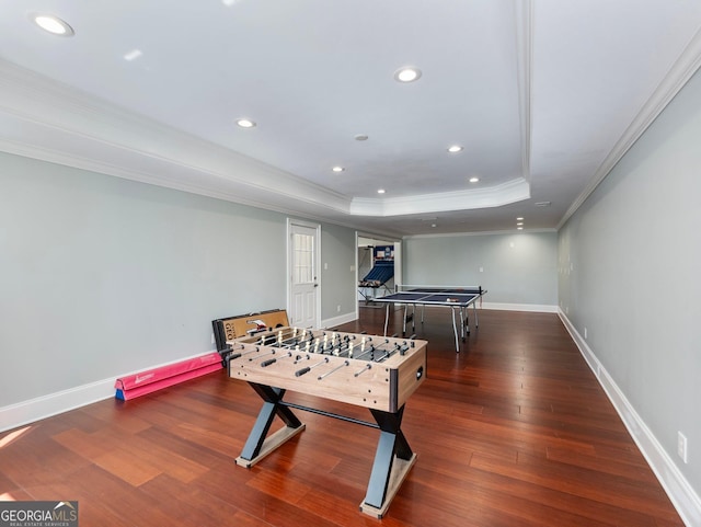 game room with a tray ceiling, recessed lighting, ornamental molding, baseboards, and wood finished floors