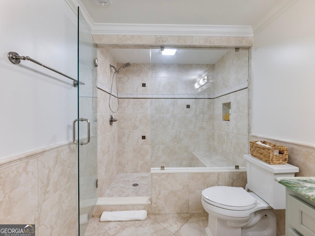 bathroom featuring vanity, ornamental molding, a shower stall, and wainscoting