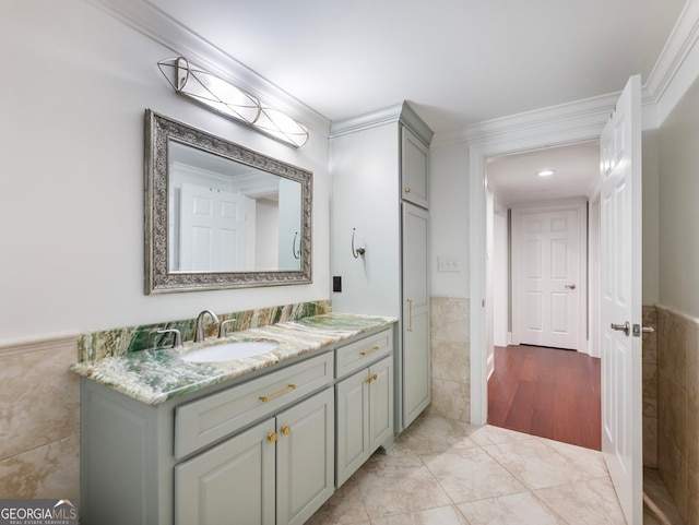 bathroom with crown molding, vanity, wainscoting, tile patterned flooring, and tile walls