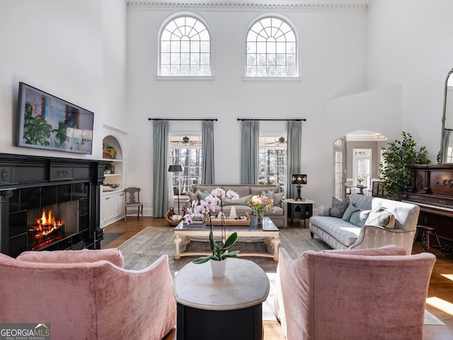 living area with a tile fireplace, arched walkways, and wood finished floors
