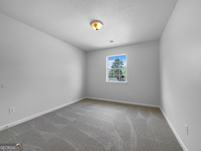 unfurnished room with carpet flooring, visible vents, a textured ceiling, and baseboards