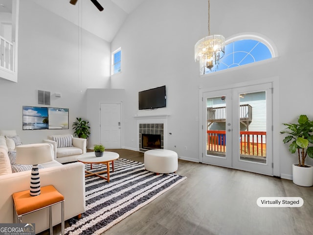 living room with wood finished floors, visible vents, a fireplace, french doors, and ceiling fan with notable chandelier