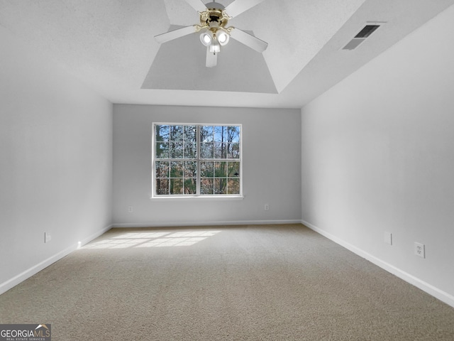 carpeted spare room with visible vents, a ceiling fan, a textured ceiling, baseboards, and a raised ceiling