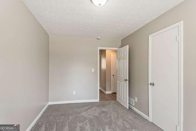 unfurnished bedroom featuring visible vents, baseboards, a textured ceiling, and carpet flooring
