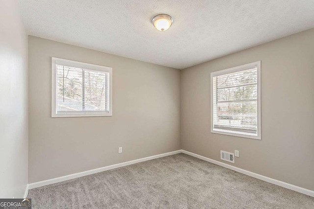 spare room with visible vents, baseboards, a textured ceiling, and carpet flooring