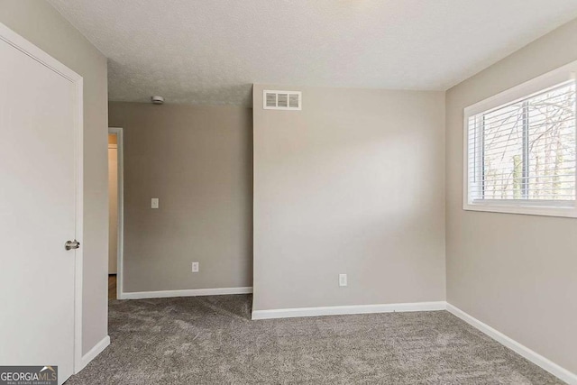 carpeted empty room with visible vents, baseboards, and a textured ceiling