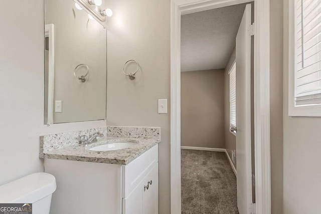 half bathroom featuring toilet, vanity, and baseboards