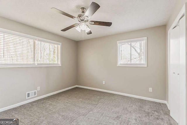 unfurnished bedroom featuring multiple windows, carpet, visible vents, and a closet