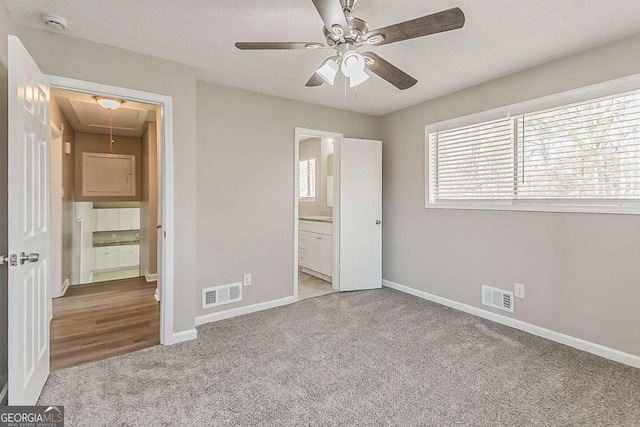 unfurnished bedroom featuring visible vents, baseboards, attic access, and carpet flooring