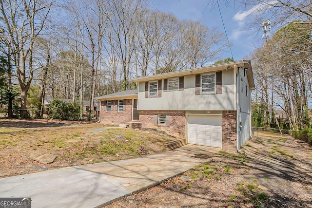 tri-level home featuring an attached garage, brick siding, and driveway
