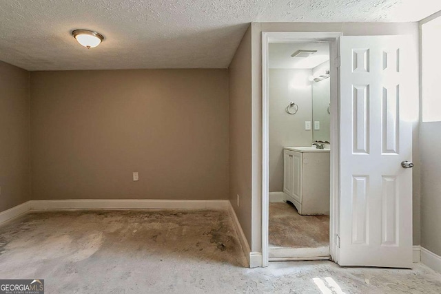 bathroom with vanity, unfinished concrete floors, baseboards, and a textured ceiling
