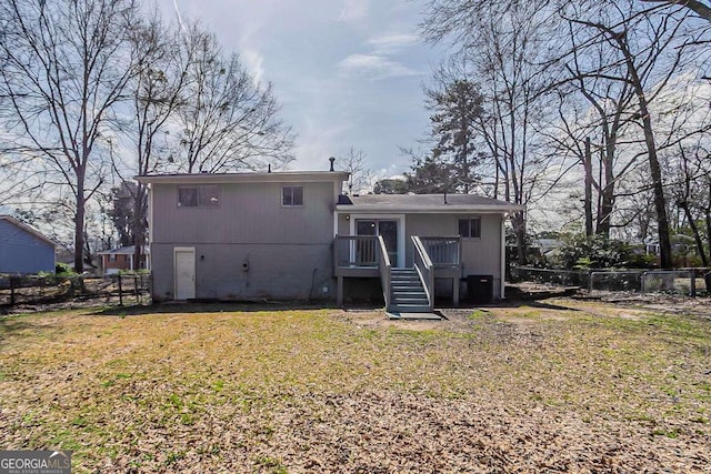rear view of property with a yard, stairs, and fence