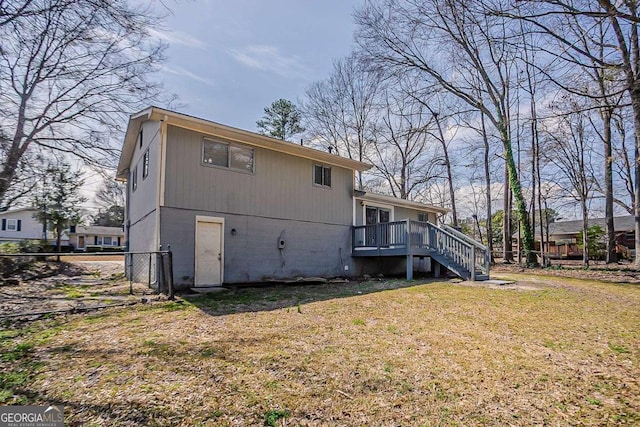 rear view of house featuring a lawn, stairs, and fence