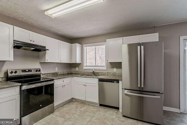 kitchen with under cabinet range hood, a sink, stainless steel appliances, white cabinets, and light tile patterned floors