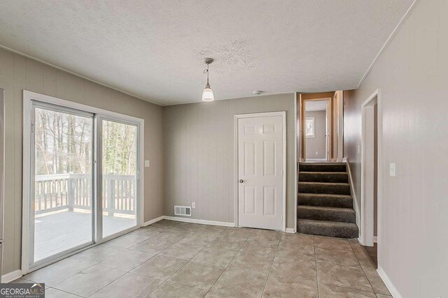 interior space with visible vents, a textured ceiling, stairway, light tile patterned floors, and baseboards