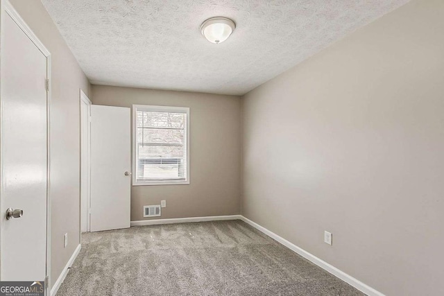 spare room with baseboards, carpet floors, and a textured ceiling