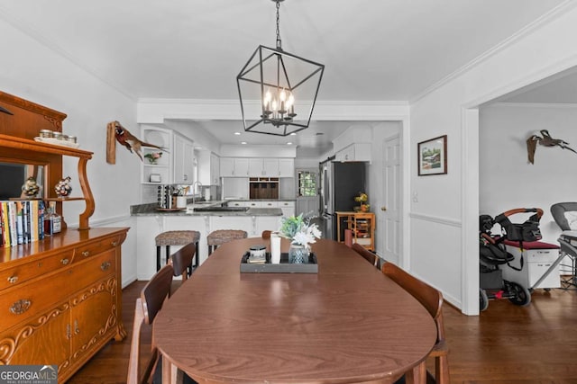 dining room featuring dark wood-style flooring, an inviting chandelier, and ornamental molding