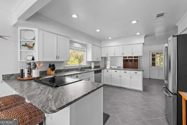 kitchen featuring visible vents, a sink, white cabinetry, stainless steel appliances, and a peninsula