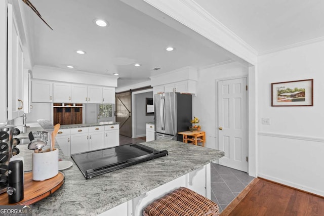 kitchen featuring white cabinets, crown molding, freestanding refrigerator, and black electric stovetop