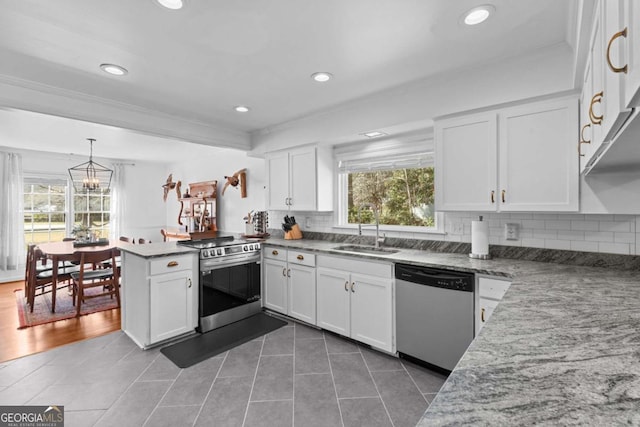 kitchen featuring a wealth of natural light, a sink, appliances with stainless steel finishes, a peninsula, and white cabinets