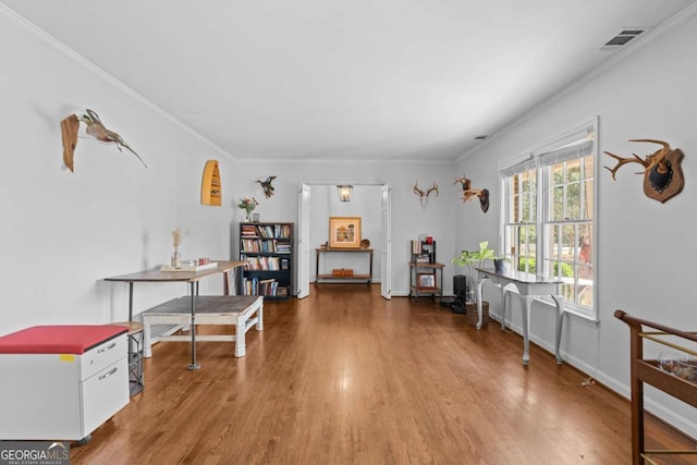 interior space featuring visible vents, wood finished floors, and ornamental molding