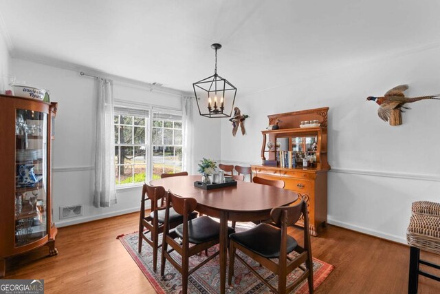 dining room with baseboards, wood finished floors, visible vents, and a chandelier