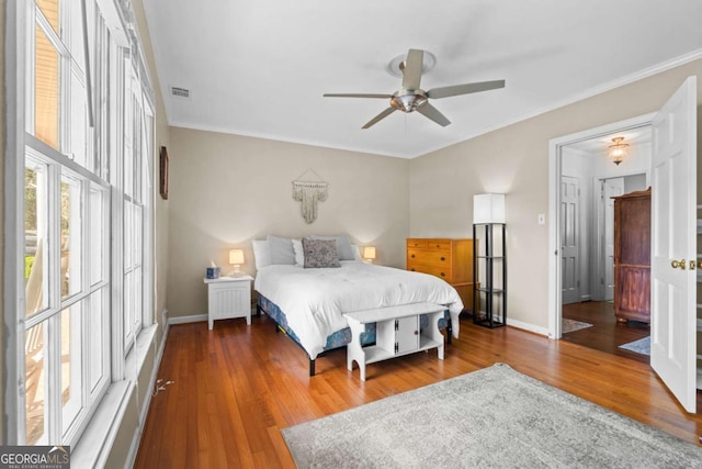 bedroom with visible vents, baseboards, wood finished floors, and ornamental molding