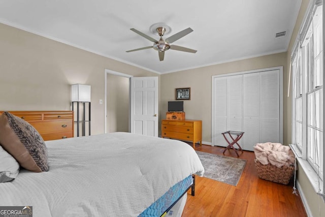 bedroom featuring a closet, visible vents, crown molding, and wood finished floors