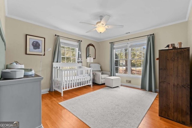 bedroom with baseboards, light wood-type flooring, and ornamental molding