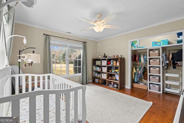 bedroom with a closet, crown molding, ceiling fan, and wood finished floors