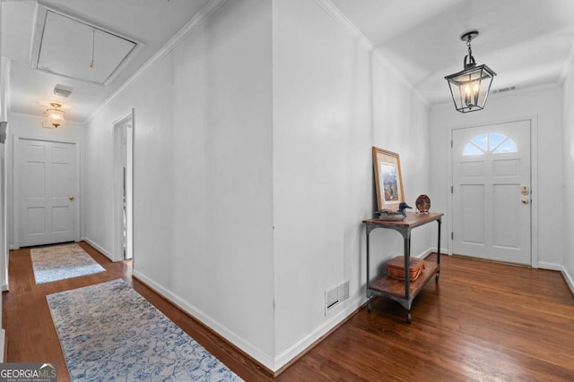 foyer featuring visible vents, wood finished floors, and ornamental molding