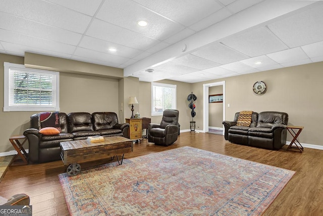 living room featuring baseboards, wood finished floors, and a paneled ceiling