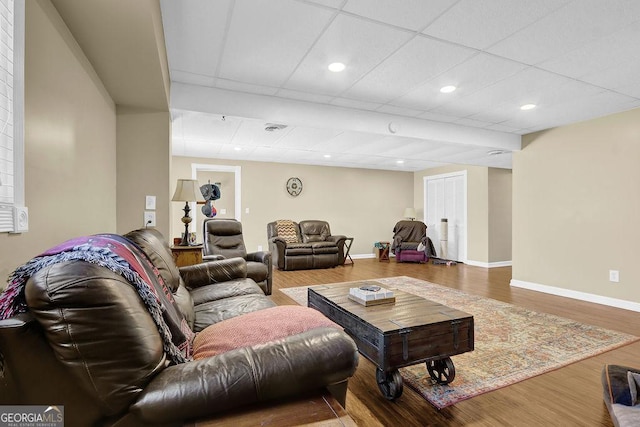 living room featuring baseboards, wood finished floors, and a drop ceiling