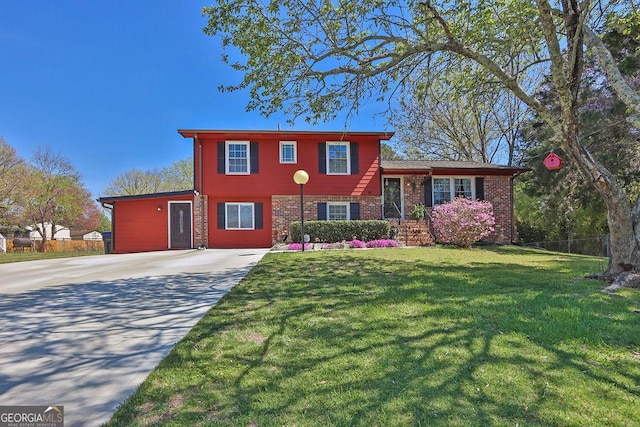 tri-level home featuring brick siding, driveway, fence, and a front lawn